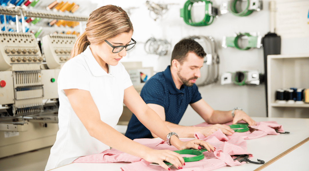 Workers placing hoops on t-shirts at an embroidery workshop – preparing garments for embroidery with precision and care.