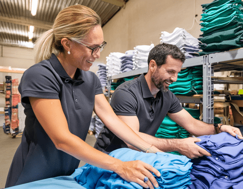 Workers folding shirts in a warehouse for an embroidery business