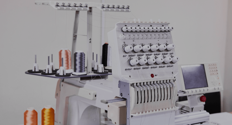 Multi-needle embroidery machine with spools of thread.